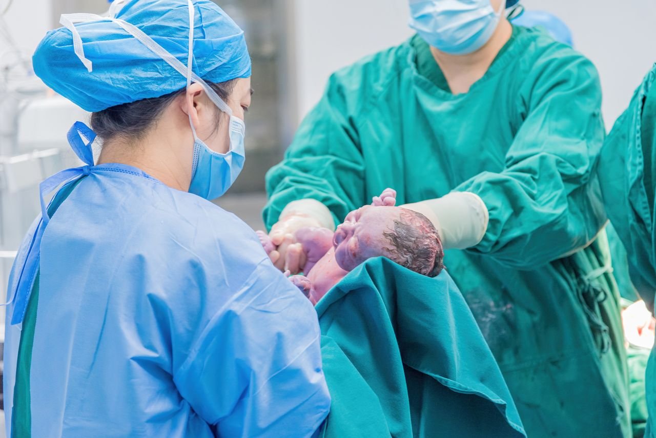 Home Medical professionals holding a newborn baby in a hospital setting, highlighting care.