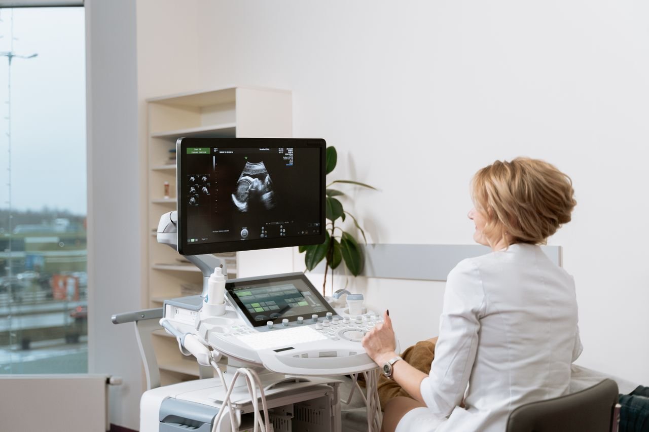 Home Doctor performing a prenatal ultrasound scan with medical equipment in a clinic.