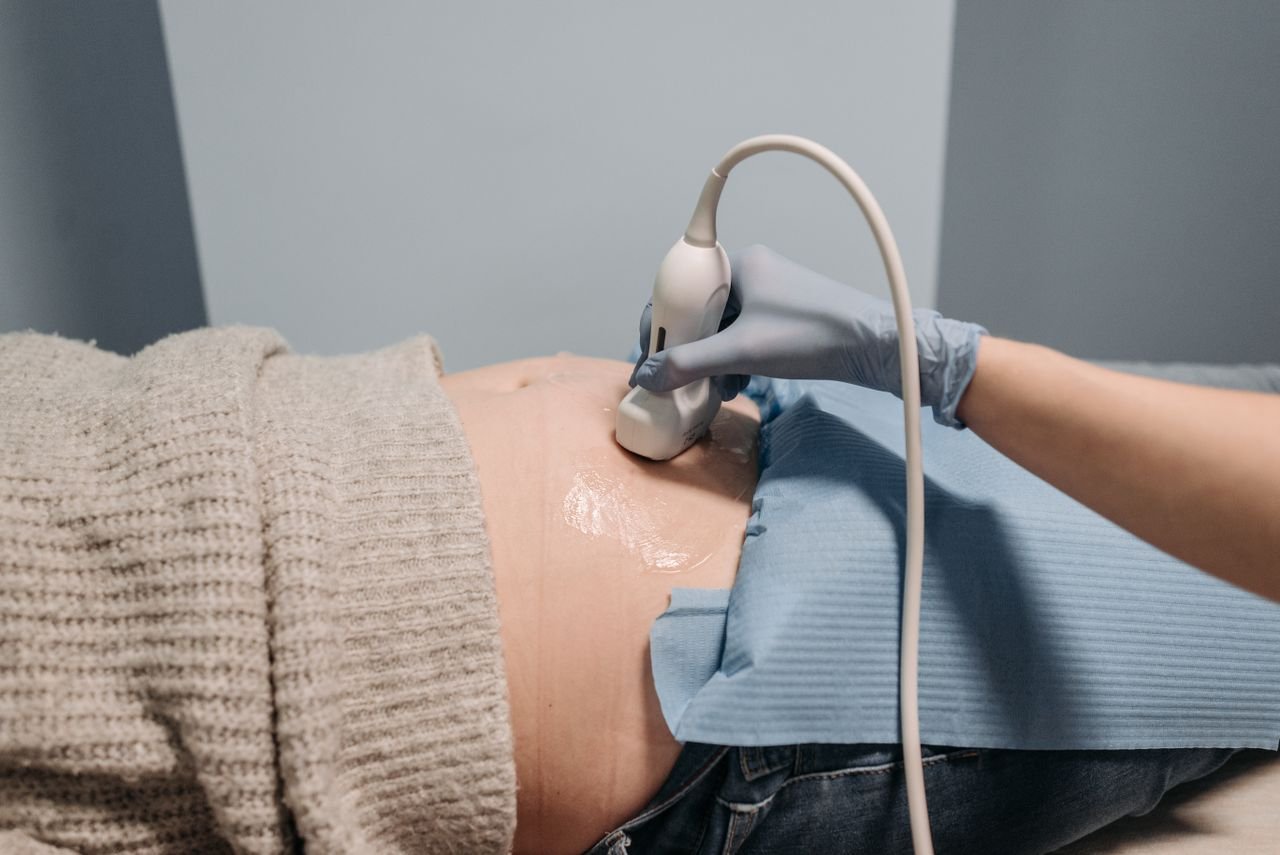 Home A healthcare professional performing an ultrasound on a pregnant abdomen.
